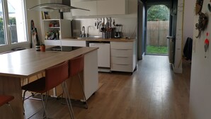 Une cuisine moderne dotée d’un îlot central, de meubles blancs et offrant une vue sur l’extérieur.