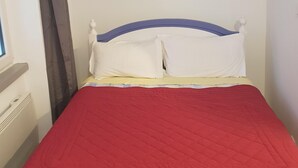 A bed with a red quilt, white pillows, and a blue headboard in a room with white walls. - Residence Terminus housing  (Clermont-Ferrand)