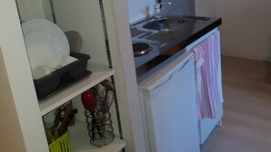 A compact kitchen with white cabinetry, a microwave, a sink, and a small refrigerator. - Residence Terminus housing  (Clermont-Ferrand)
