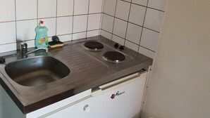A compact kitchen with a sink, two burners, and a small countertop. - Jaude Residence Stay 4 (Clermont-Ferrand)