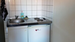 A compact kitchen with a sink, two burners, a dishwasher, and a trash bin. - Jaude Residence Stay 4 (Clermont-Ferrand)