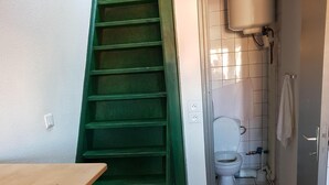 A narrow hallway with a green staircase leading to a bathroom. - Jaude Residence Stay 4 (Clermont-Ferrand)