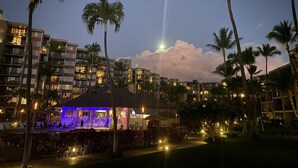 Een resort met meerdere gebouwen, palmbomen en een verlichte bar in de schemering.