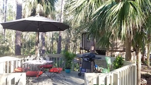 Patio esterno con tavolo e sedie, un barbecue e un ombrellone grande.