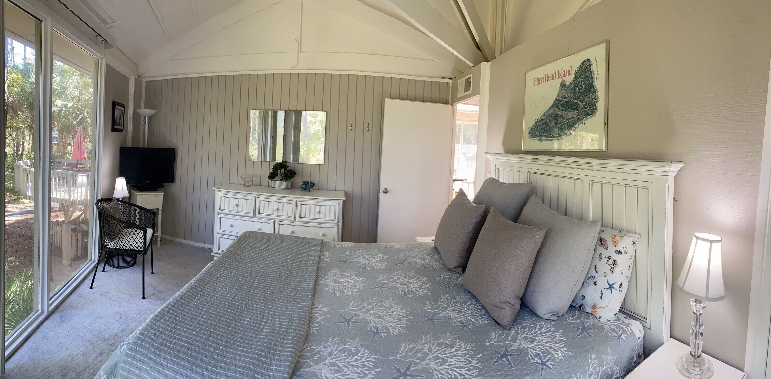 Een slaapkamer met een bed, een dressoir, een televisie en een kaart aan de muur.