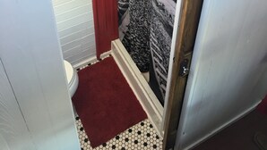 Een badkamer met toilet, een rode douchegordijn en een behang met patroon.