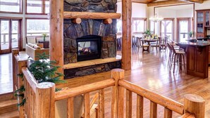 A spacious interior with a stone fireplace, wooden beams, and a dining area.