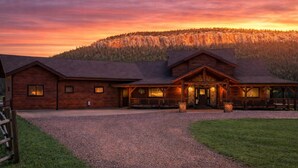 A wooden lodge with a gravel driveway and a mountain backdrop.