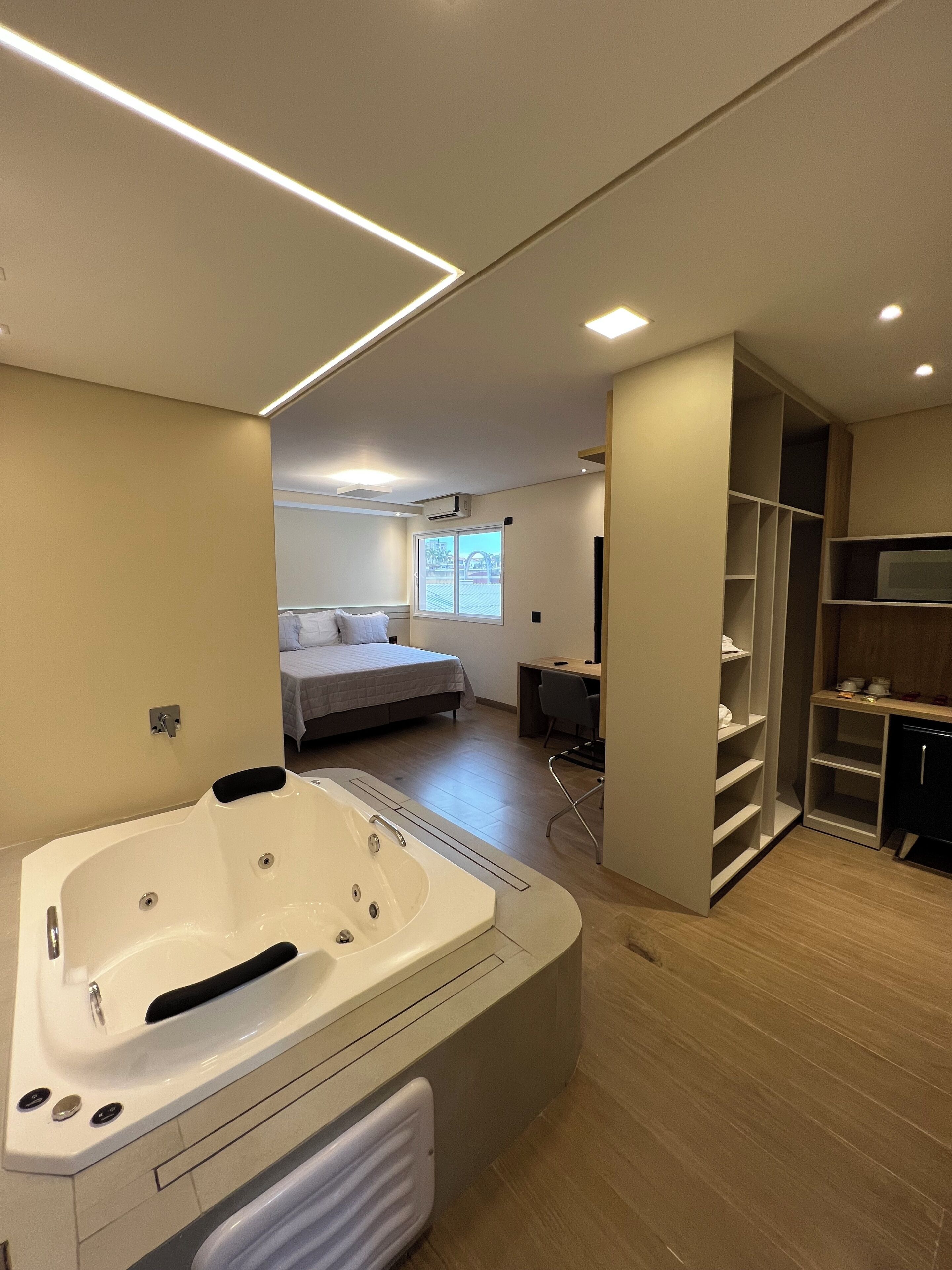 A modern bathroom with a large bathtub, a shower area, and a walk-in closet.