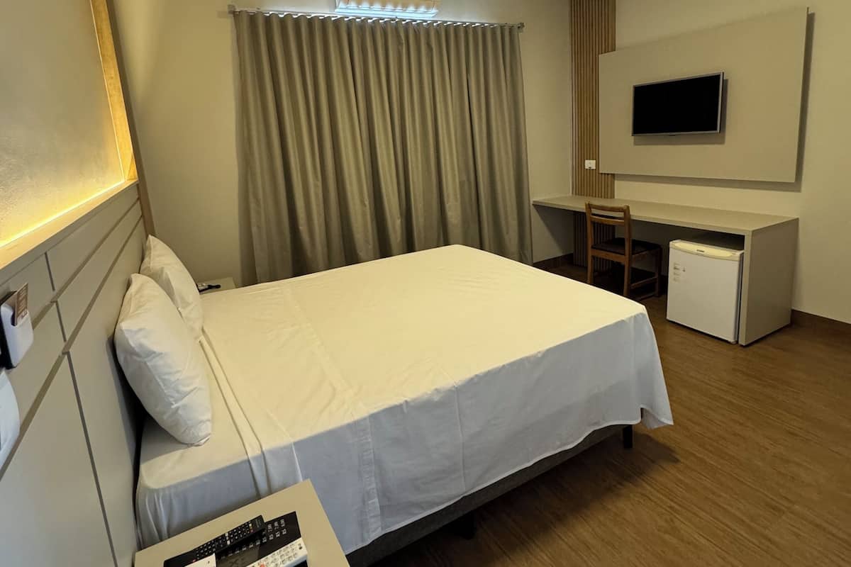 Une chambre d’hôtel équipée d’un lit, d’un bureau, d’une télévision et d’un climatiseur.