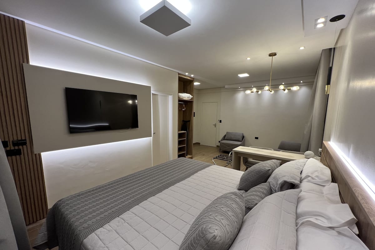 Une chambre d’hôtel moderne dotée d’un grand lit, d’un téléviseur à écran plat fixé au mur, d’un bureau avec une chaise et d’une armoire.