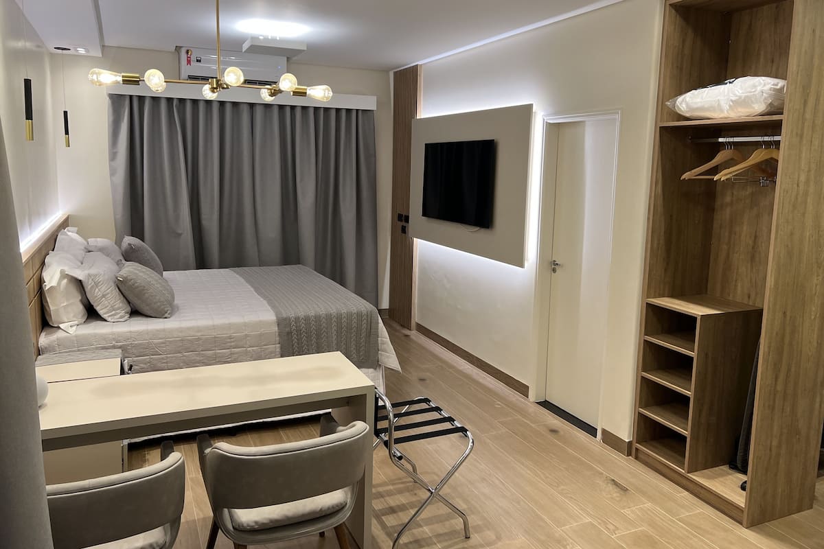 Une chambre moderne comprenant un lit, une table de chevet, des chaises, un téléviseur et une armoire en bois.