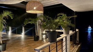 Una terrazza esterna con piante in vaso, un lampadario e vista sull'acqua.