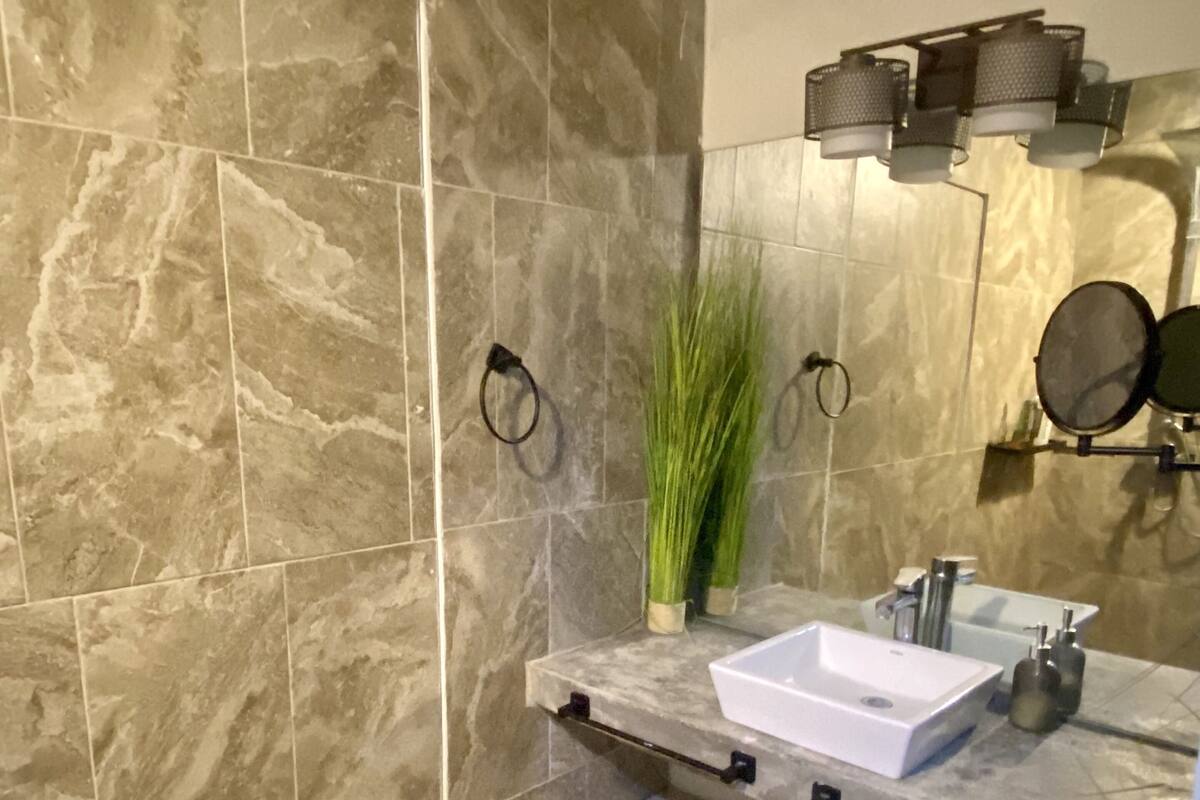 Une salle de bain moderne avec une douche à l’italienne, un lavabo blanc et un miroir au-dessus.