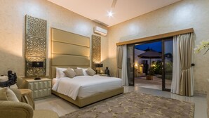 Un dormitorio moderno con una cama grande, una mesita de noche, un sofá y vistas al exterior a través de una puerta corredera.