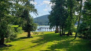 A grassy area with a bridge over a body of water, surrounded by trees. -  San Juan Island Beach House, Waterfront Lodging just minutes from Roche Harbor! (Friday Harbor)