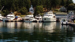 A marina with several boats docked, a white church, and a forested hillside in the background. -  San Juan Island Beach House, Waterfront Lodging just minutes from Roche Harbor! (Friday Harbor)