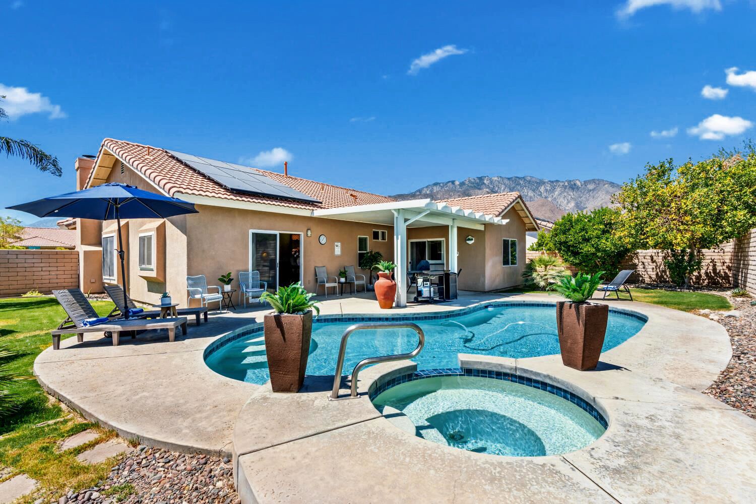 A residential property with a swimming pool, outdoor seating, and a mountain backdrop.