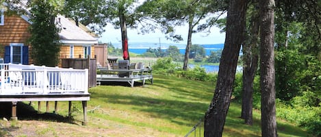 A wooden house with a deck, a hammock, and a view of the water.