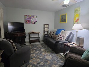 A living room with a sofa, a TV, a lamp, and artwork on the walls. - Englewood Cozy Comfy Home  (Englewood)