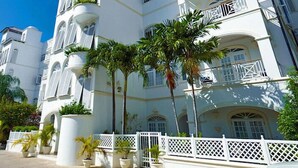 A large, white, multi-story building with balconies and palm trees. - Condo Old Trees 6 - Firefly (Paynes Bay)