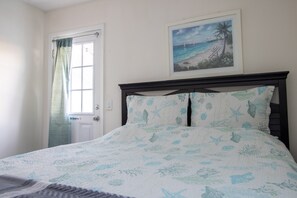 A bedroom with a bed, a framed picture of a beach scene, and a 'No Smoking' sign on the door. - OceanView Oasis - Relax with Hot Tub, Breakfast, Fire Pit & Putting Green! (Panama City Beach)