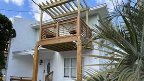 Et toetagers hus med en træbalkon, en hoveddør og en lille veranda.