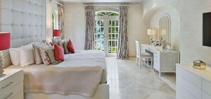A bedroom with a large bed, a vanity with a mirror, and a desk.