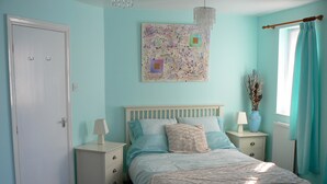 Une chambre à coucher comprenant un lit, des tables de chevet, une commode, un lustre et une fenêtre avec des rideaux.
