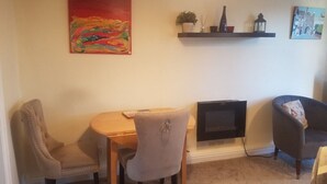 Un salon avec une cheminée, une table à manger avec des chaises et un téléviseur fixé au mur.