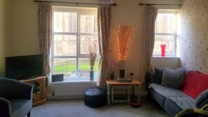 Un salon comprenant un téléviseur, un canapé et une petite table agrémentée d’objets décoratifs.