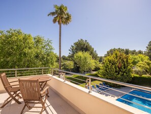 Un espace aménagé au bord de la piscine, avec une table et des chaises, un palmier et une vue sur la végétation environnante.