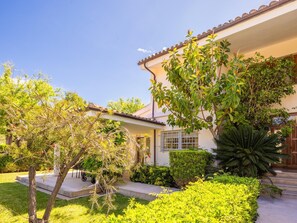 Une maison dotée d’un porche abrité, d’un jardin bien entretenu et surplombée d’un ciel dégagé.