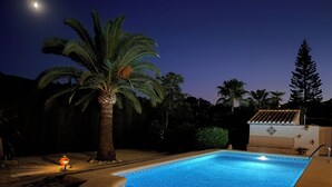 A swimming pool with a curved edge, surrounded by palm trees and a tiled building. - 3 bed 2 bath family villa, close to beach, Smart TV, WIFI and air con (Javea)