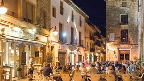An outdoor café with tables and chairs, surrounded by buildings with balconies and signage. - 3 bed 2 bath family villa, close to beach, Smart TV, WIFI and air con (Javea)