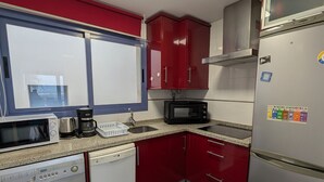 Una cocina compacta con lavadora, microondas y refrigerador.