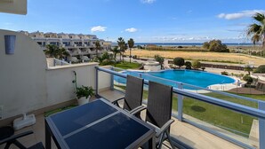 Un balcón con piscina, sillas y una mesa.