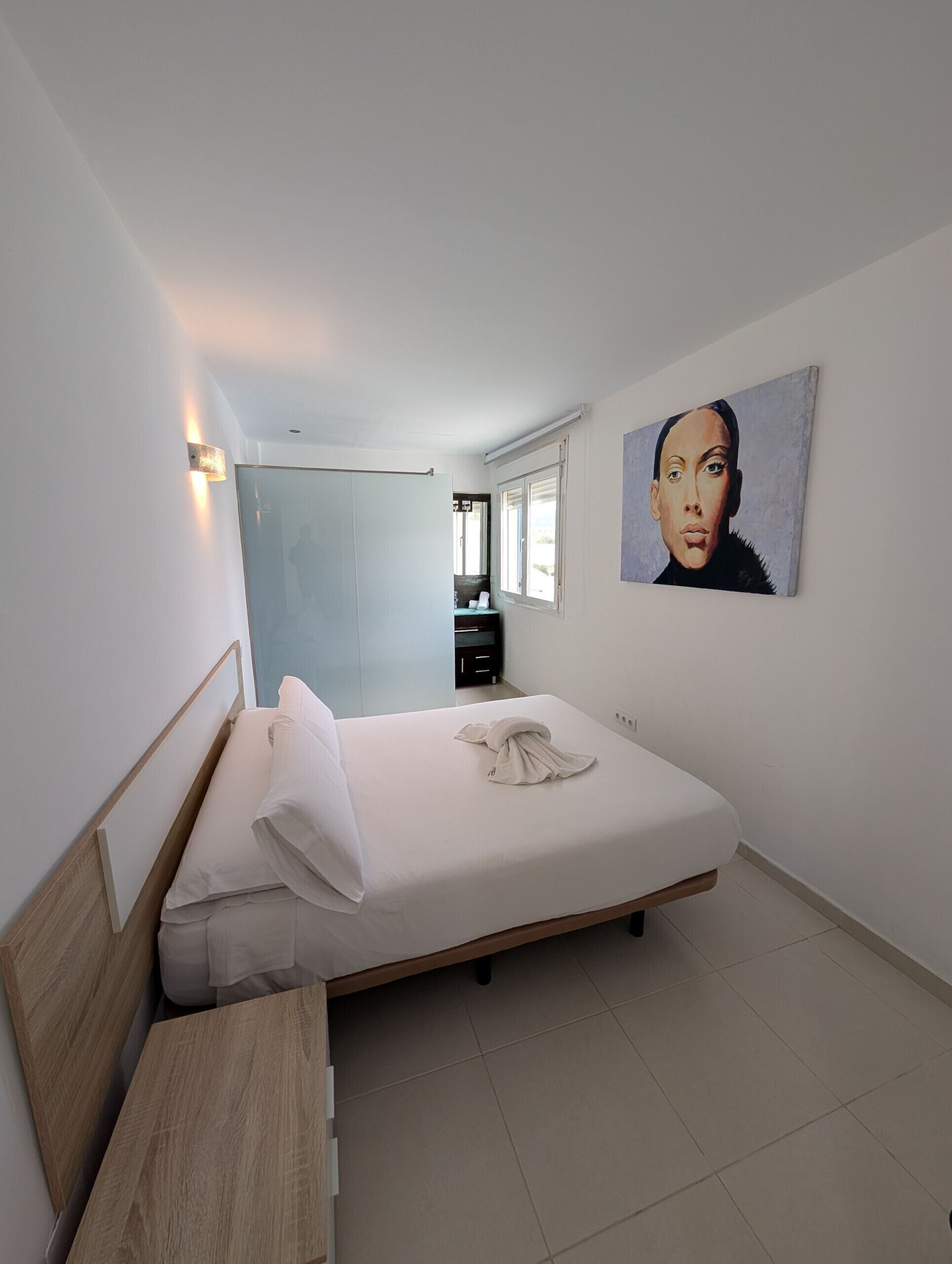 Une chambre à coucher avec un lit, une table de chevet et un tableau accroché au mur.