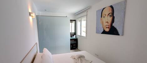 Une chambre à coucher avec un lit, une table de chevet et un tableau accroché au mur.