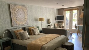 A bedroom with a large bed, bedside tables, a TV, a chair, and a window.