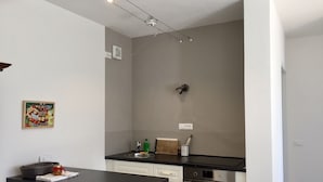 A modern kitchen with a black countertop, white cabinets, a stainless steel oven, and a wall-mounted light fixture. - Sea-view cottage a stone's throw from the beach near Capoliveri (Capoliveri)