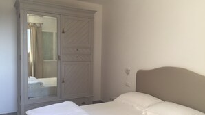 A bedroom with a bed, a wardrobe, and a mirror. - Sea-view cottage a stone's throw from the beach near Capoliveri (Capoliveri)