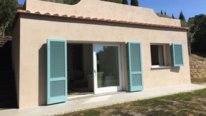 A modern building with a beige facade, large glass doors, and blue shutters. - Sea-view cottage a stone's throw from the beach near Capoliveri (Capoliveri)