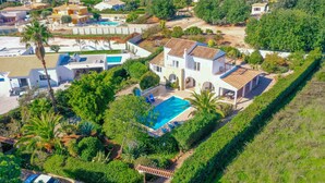 A large house with a swimming pool, surrounded by lush greenery and a hilly landscape. - Beautiful, Private Family Villa with Great Pool and access to Beaches, Mountains (Monte Canelas, Nr Alvor, District of Portimão)