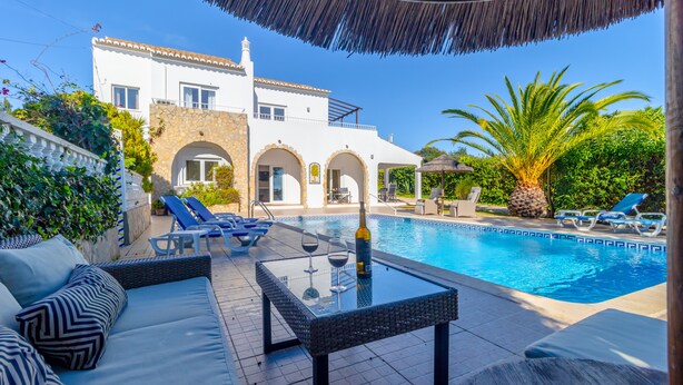 A poolside area with a sofa, lounge chairs, and a table with a bottle and glasses. - Beautiful, Private Family Villa with Great Pool and access to Beaches, Mountains (Monte Canelas, Nr Alvor, District of Portimão)