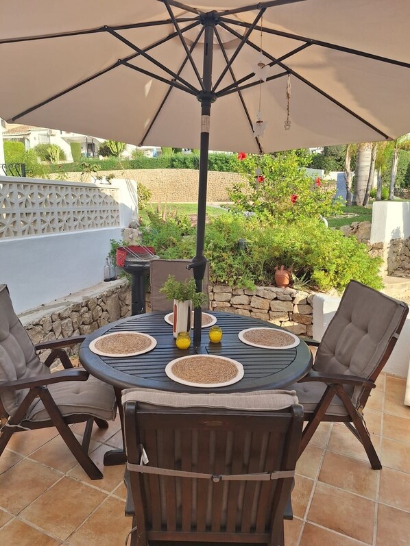 An outdoor patio with a round table, four chairs, and a large umbrella.
