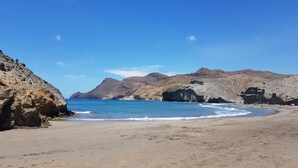 Ein Strand mit schroffen Klippen und klarem, blauem Wasser.