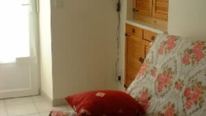 Una stanza con un divano a motivi floreali, un armadietto in legno e una porta bianca.