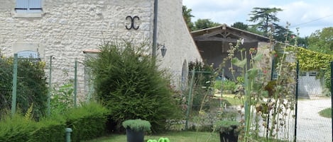 Ein Steinhäuschen mit Schornstein, ein kleiner Garten mit einem grünen Boot und einem Zaun.