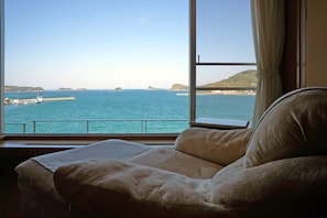 Un lit donnant sur la mer, avec une vue par la fenêtre.